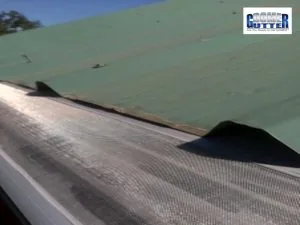 Corrugated metal roof with a GutterDome gutter guard, close view of the light green run