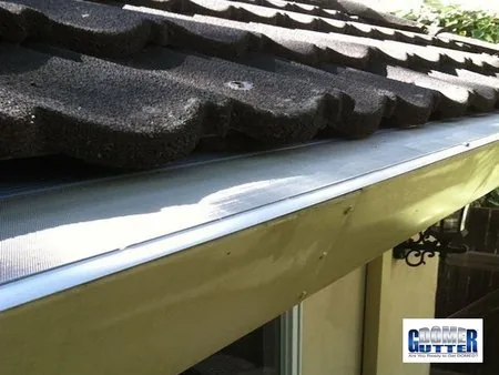Flat tile roof with GutterDome gutter guard — scalloped.