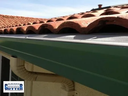 Spanish tile roof with GutterDome gutter guard — green gutter.