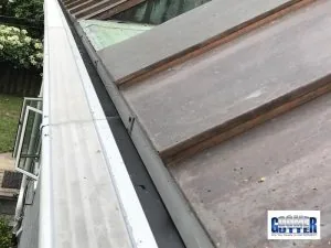 Standing seam metal roof with a GutterDome Adjustable gutter guard on half-round gutters above a backyard