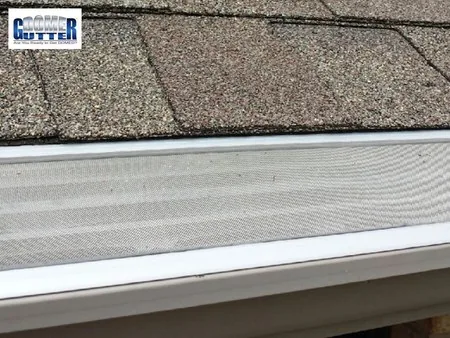 Asphalt shingle roof with GutterDome gutter guard — gray shingle straight run, close up.