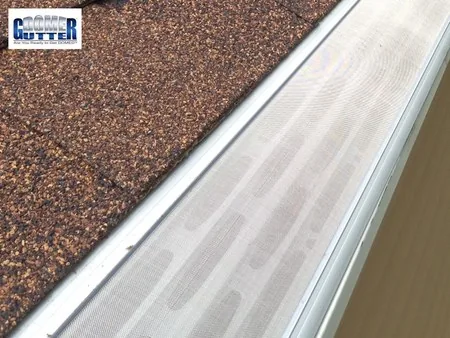 Asphalt shingle roof with GutterDome gutter guard — red shingle straight run, close up.