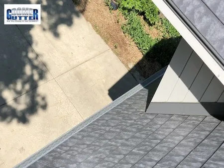 Slate tile roof with GutterDome Magma gutter guard — top view toward the driveway.